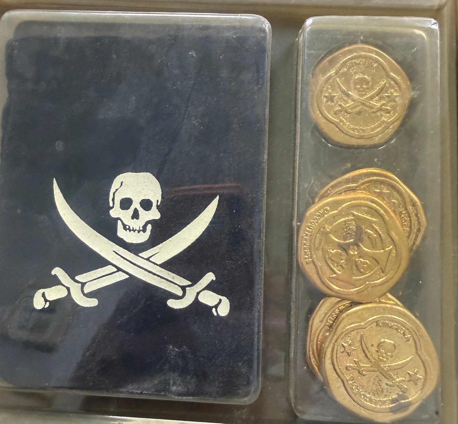 Three gold coins in a display case with a pirate emblem on a black background.