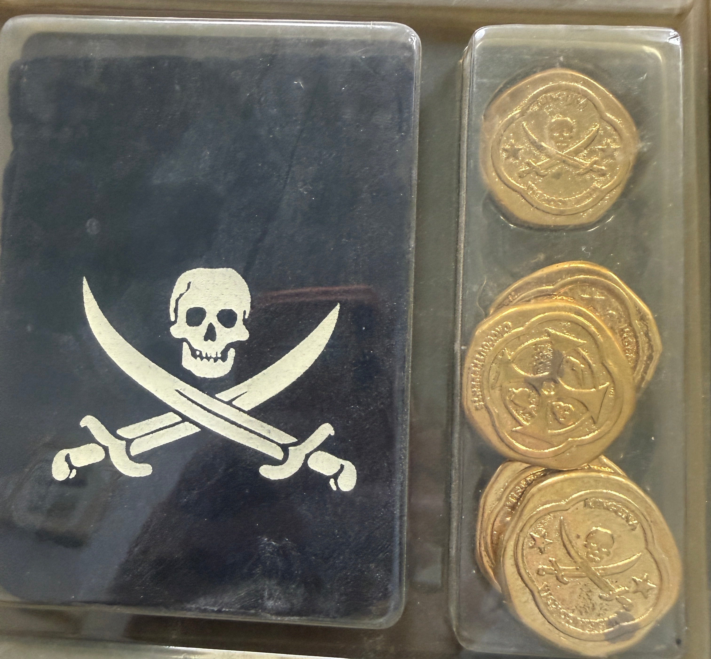 Three gold coins in a display case with a pirate emblem on a black background.