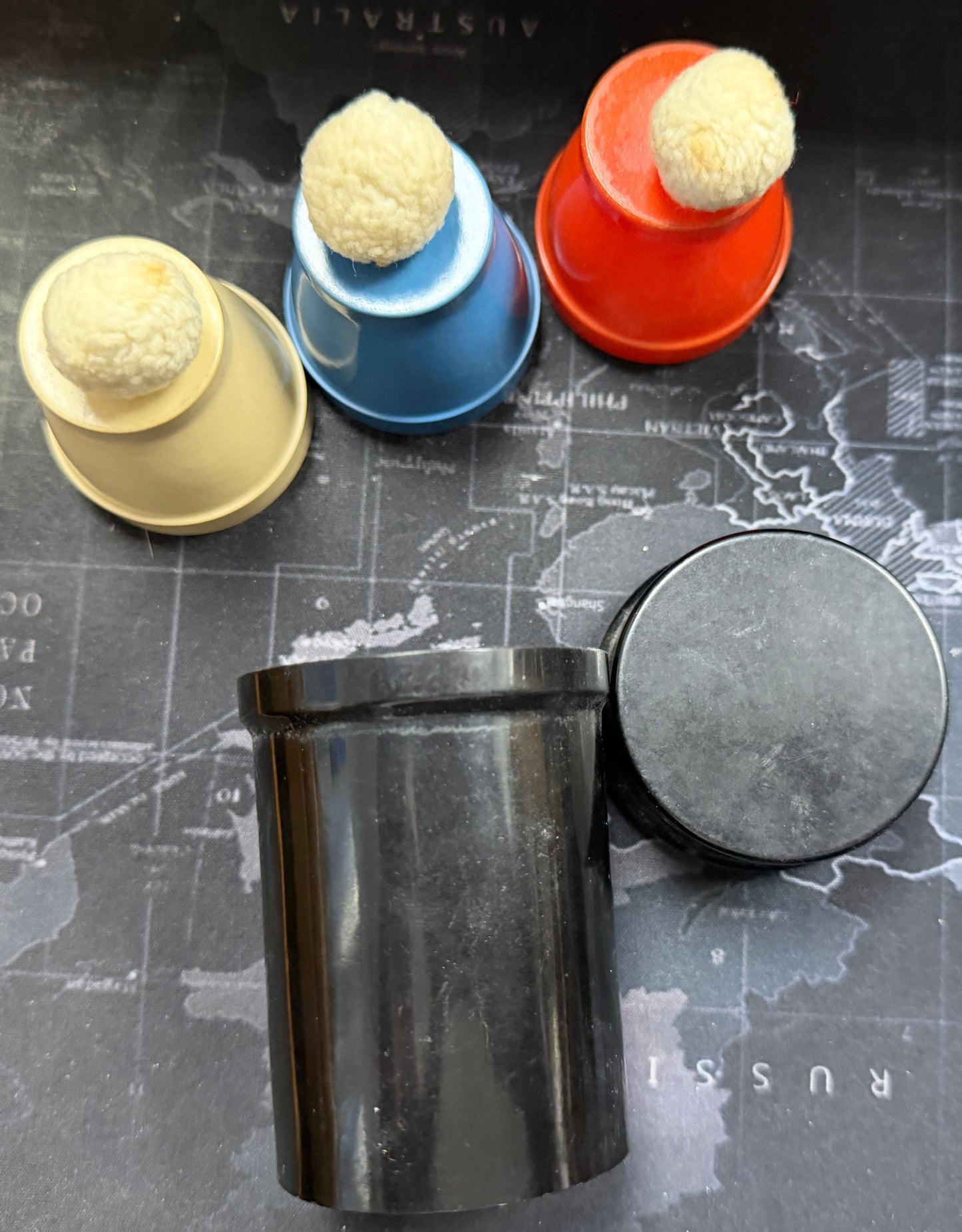Colorful cylindrical objects on a map with a black cylindrical container.