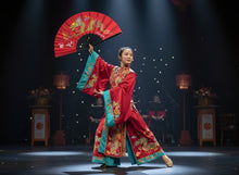 Red fan with green dragon design held by a hand against a white wall.