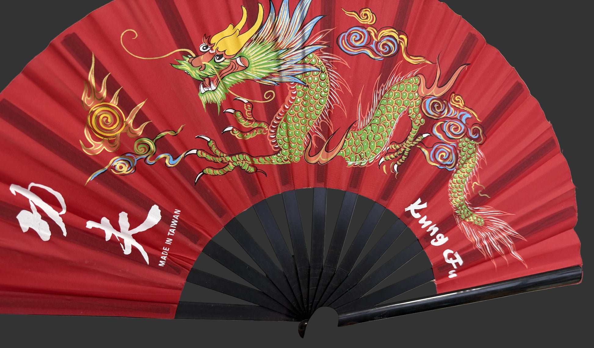 Red fan with dragon design held by a person, featuring white text on a blurred background.