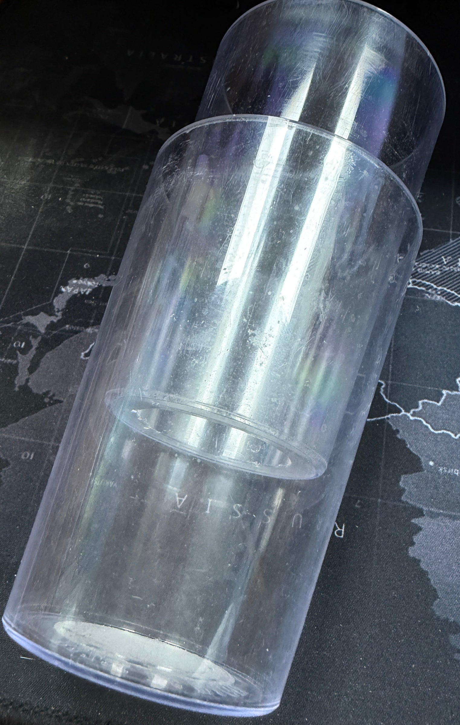 Clear cylindrical object on a dark surface with a map background