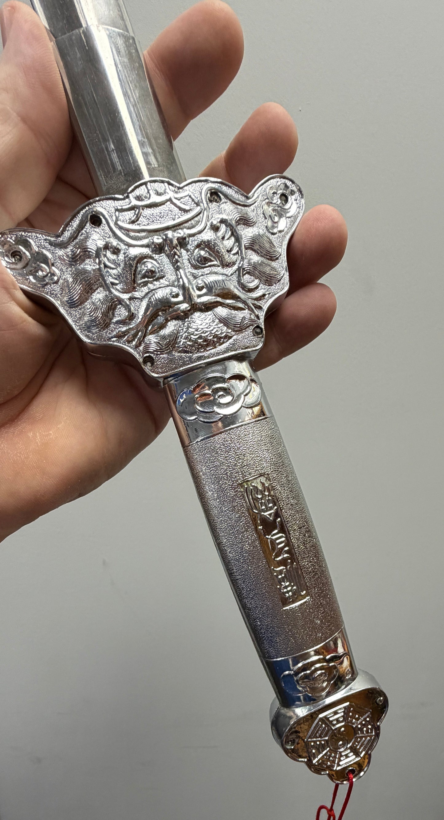 Decorative silver sword held by a person with a plain background