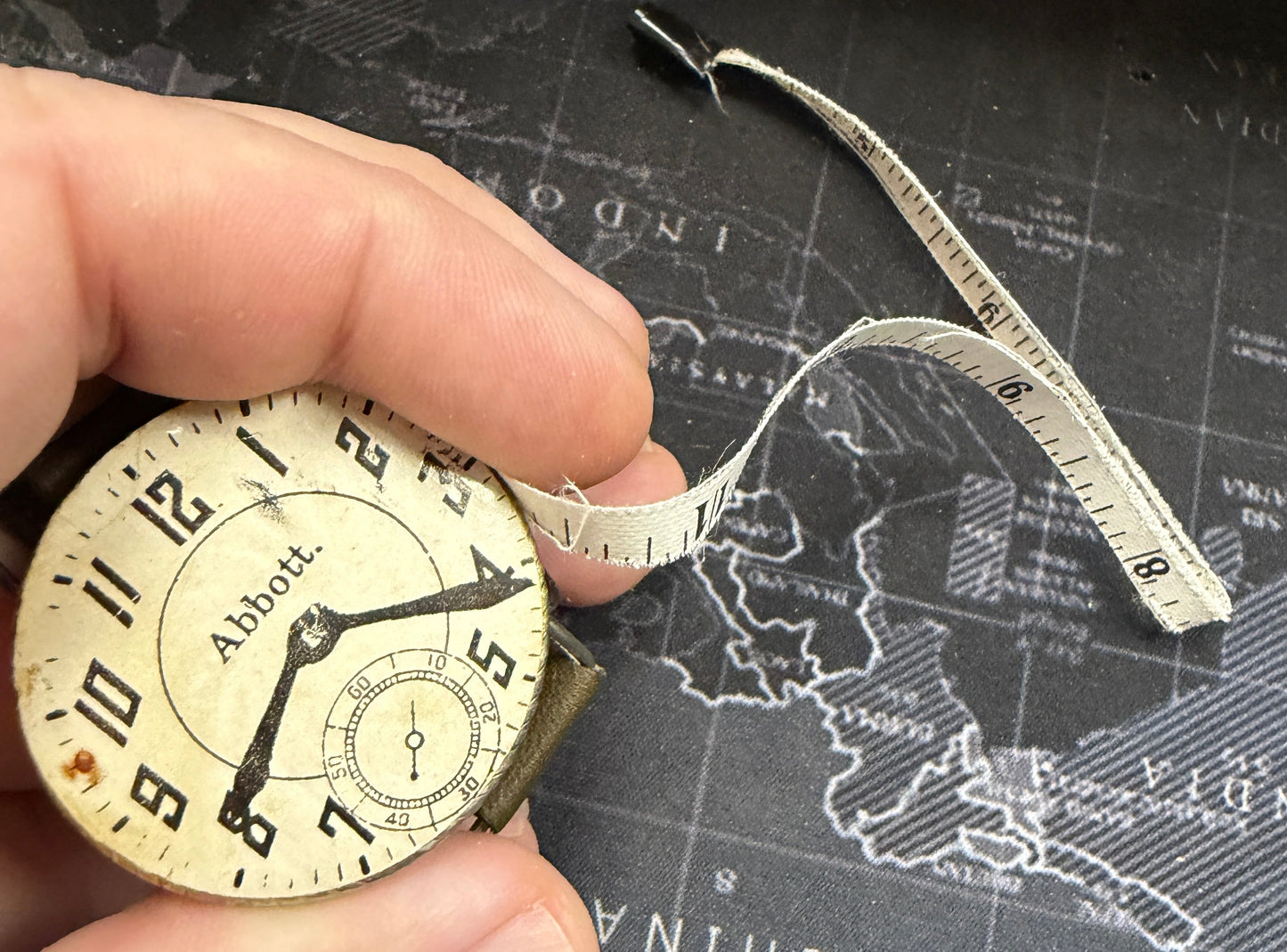 Vintage pocket watch held by a hand with a map of Australia in the background