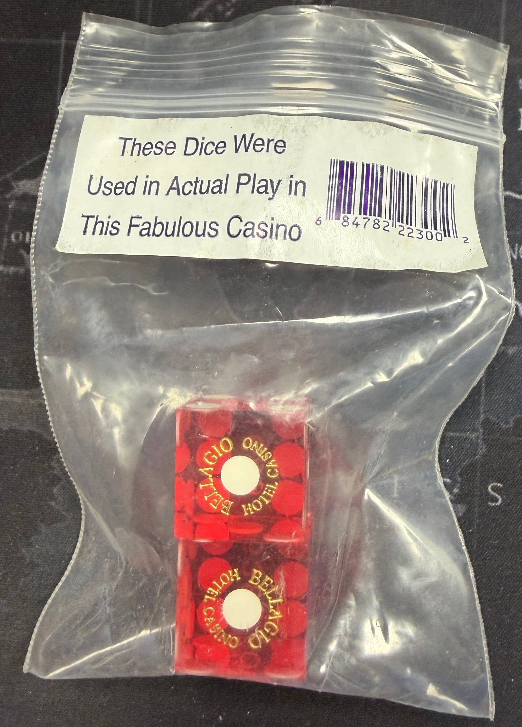 Two red dice in a clear plastic bag with a label on a map background
