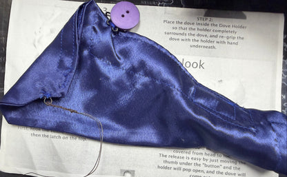 Purple satin bag with a button on top of a printed manual