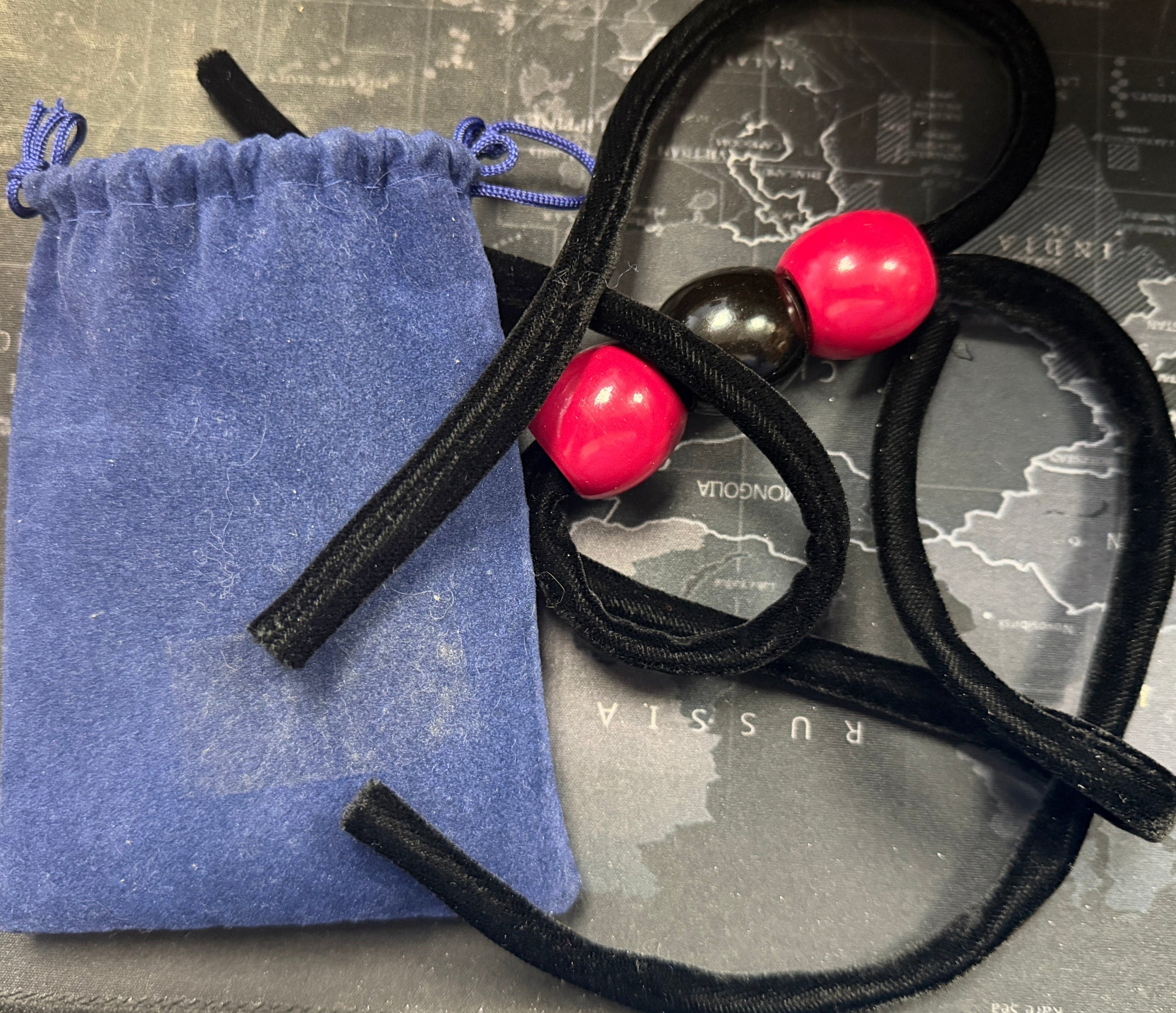 Black hair ties with pink beads on a map background