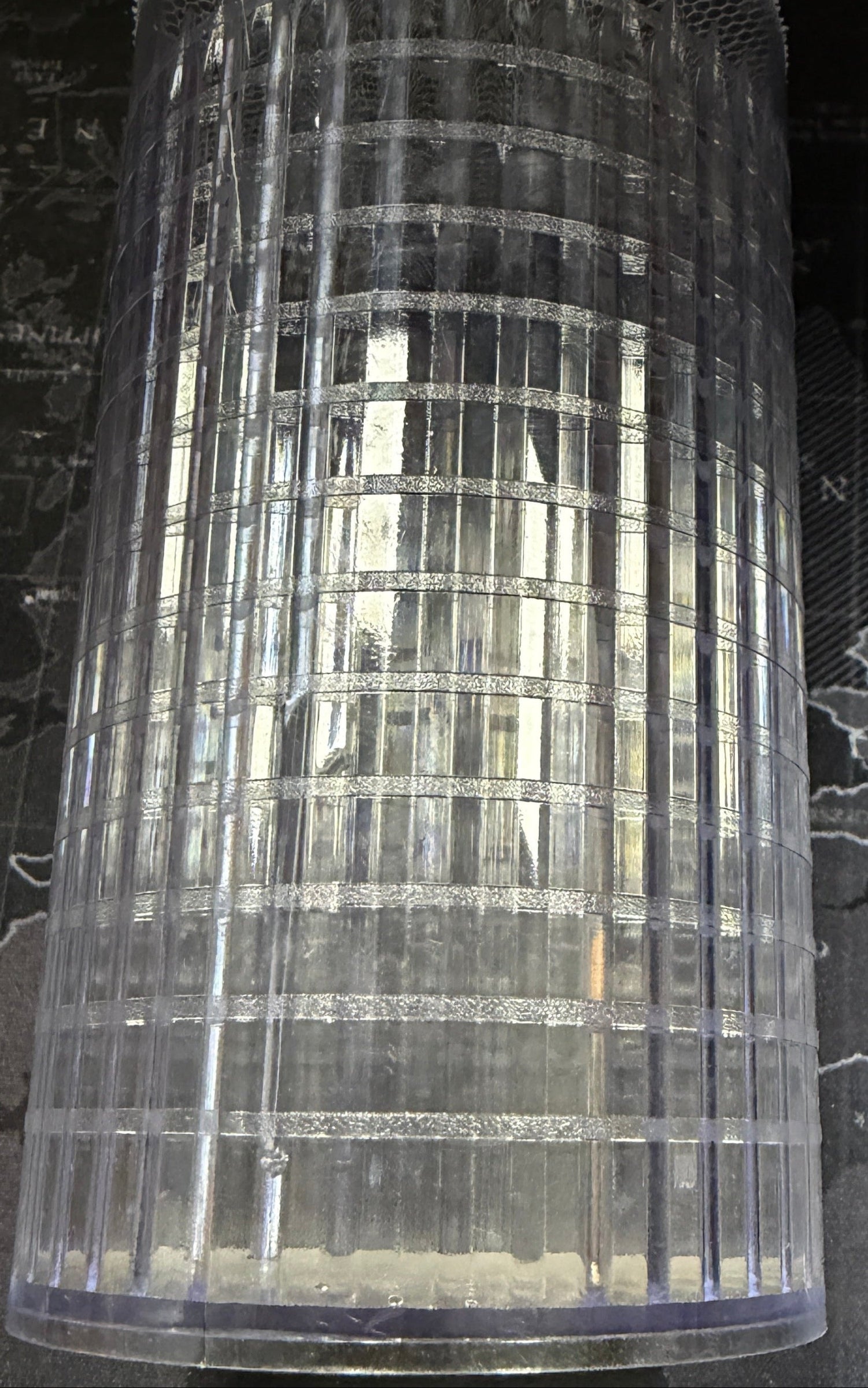 Clear cylindrical mesh container on a dark surface with a map
