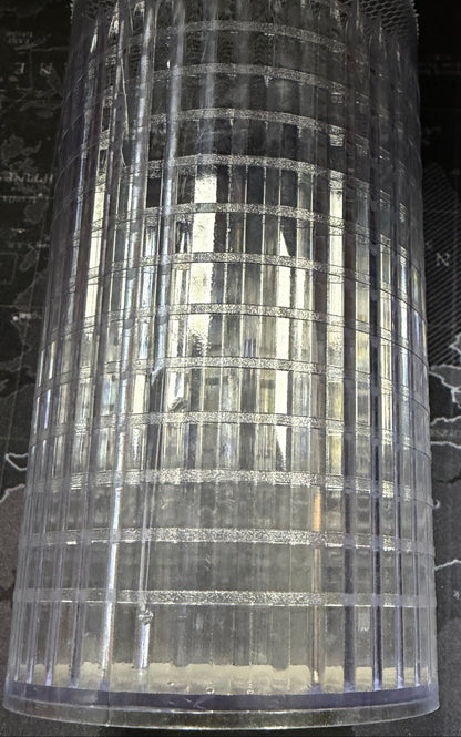 Clear cylindrical mesh container on a dark surface with a map