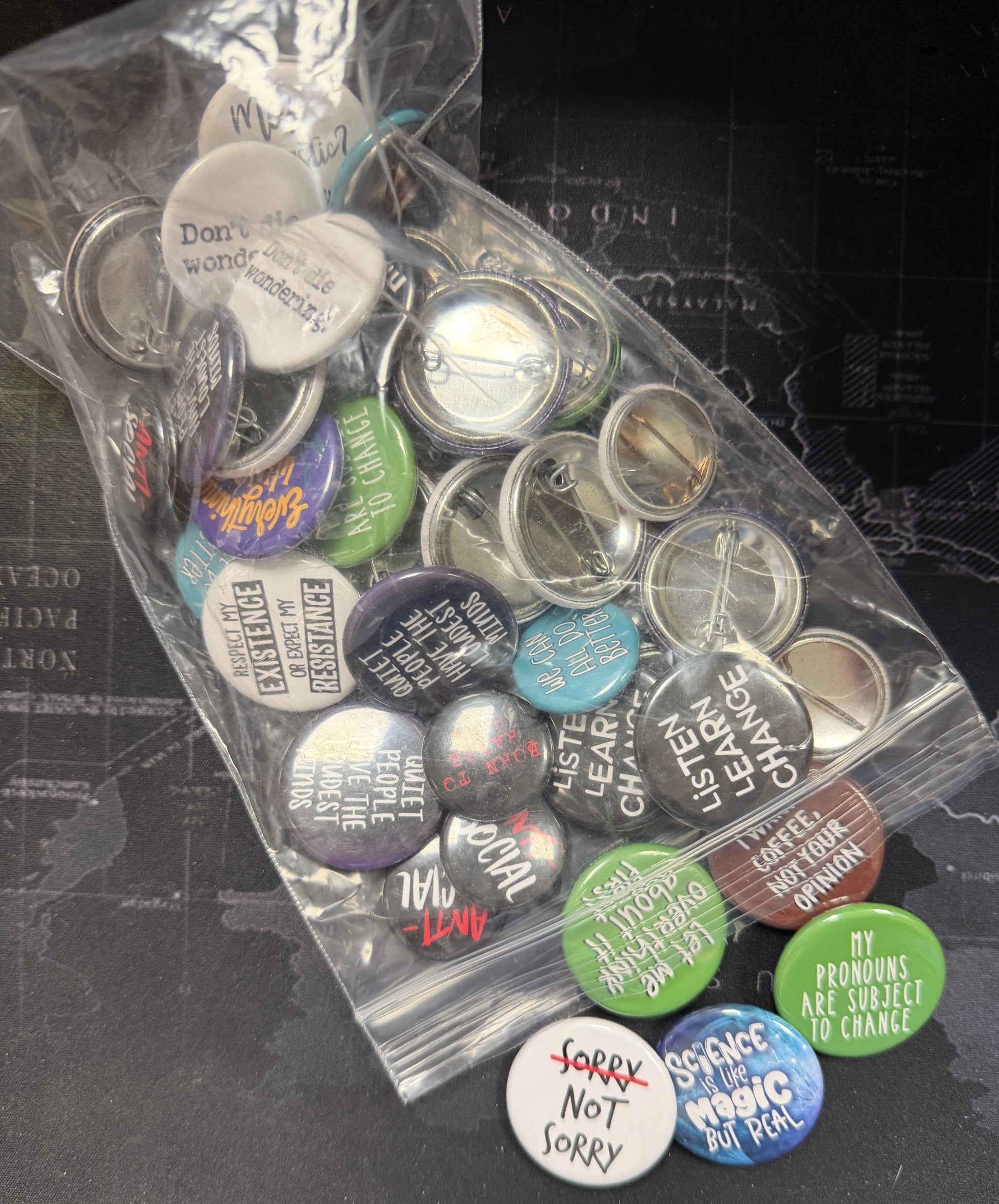 Collection of buttons with various designs and text on a black surface