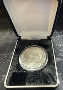 Silver coin in a display case on a map background