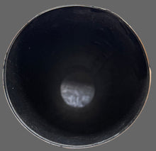 Hand holding a black cylindrical object with a blurred background