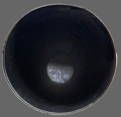 Hand holding a black cylindrical object with a blurred background