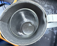 Metallic container with a glass-like interior on a dark surface