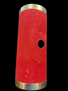 Red cylindrical object with brass ends on a desk