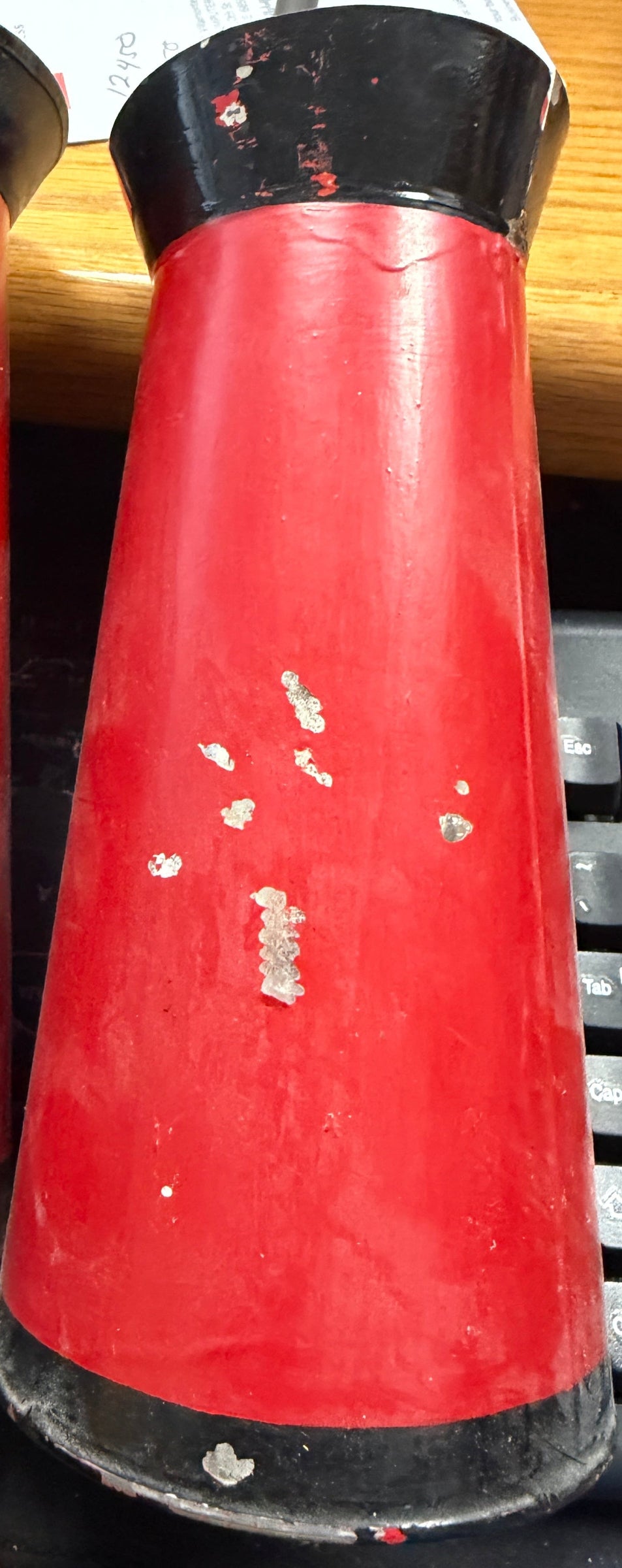 Two red cylindrical objects with black ends on a wooden surface.