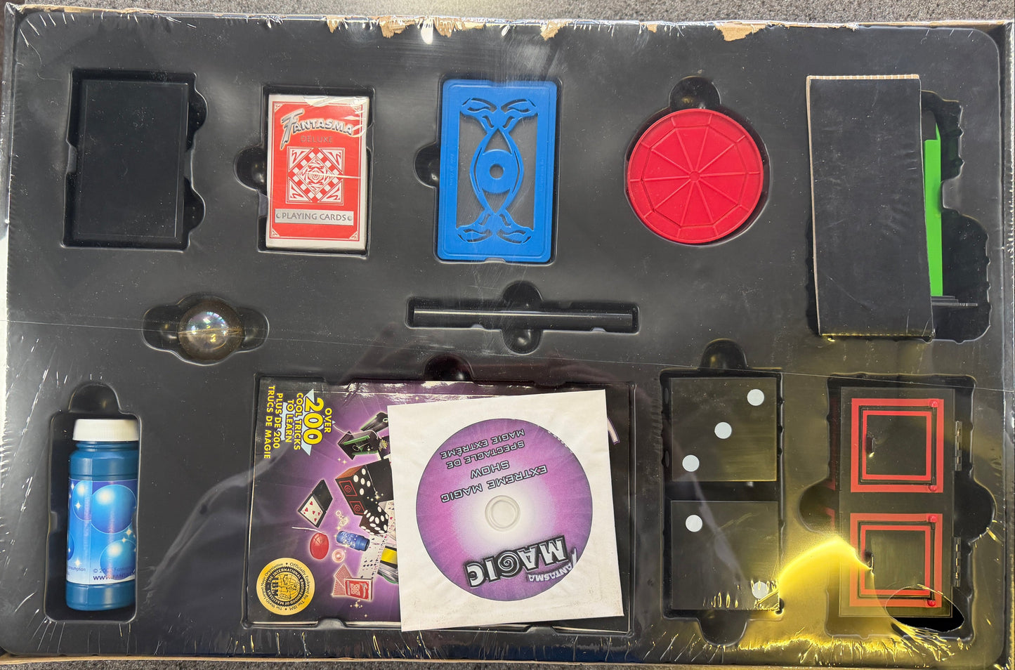 Collection of trading cards and a DVD in a black display case on a gray surface.