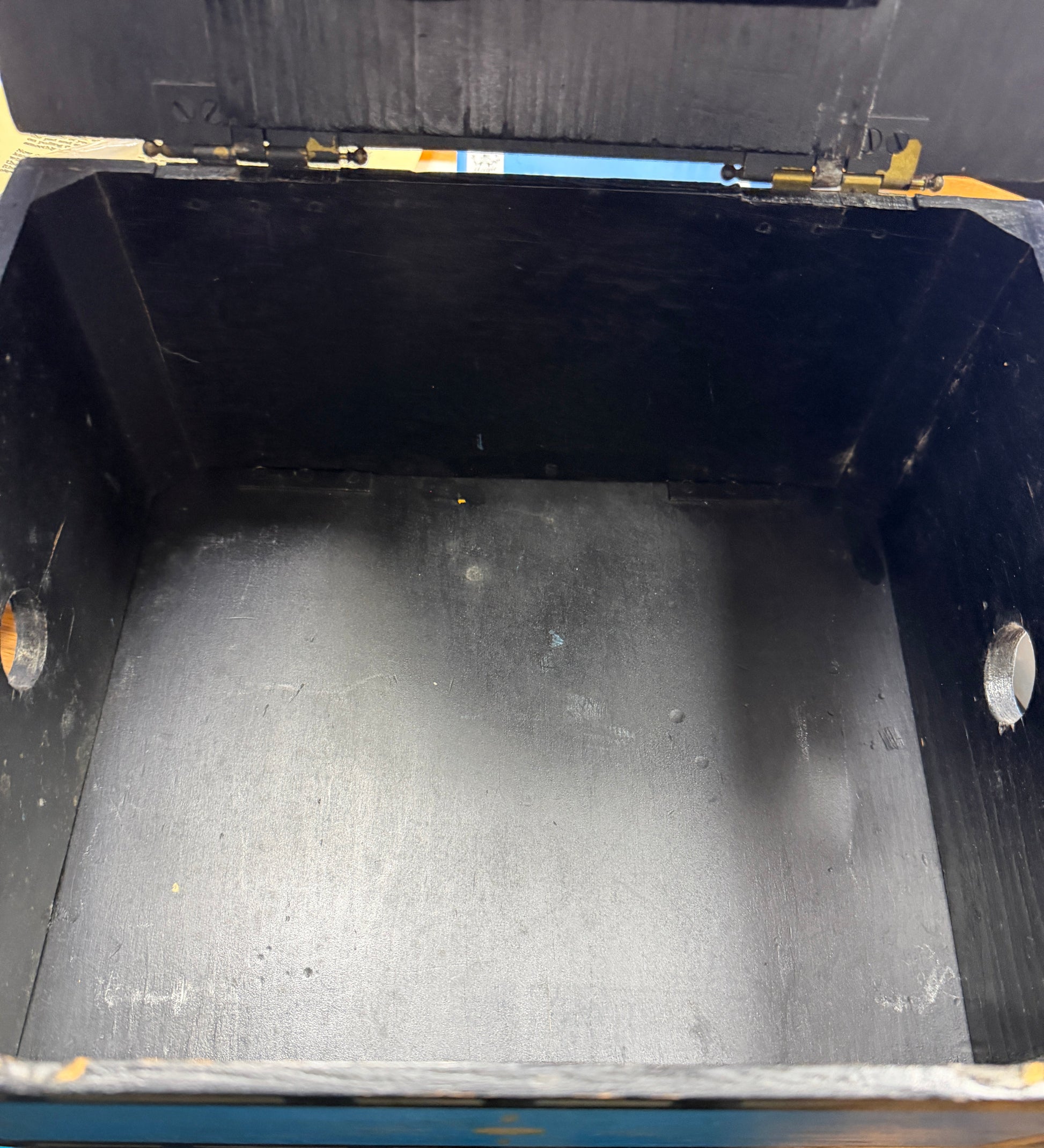 Empty black metal container with a lid on a concrete floor