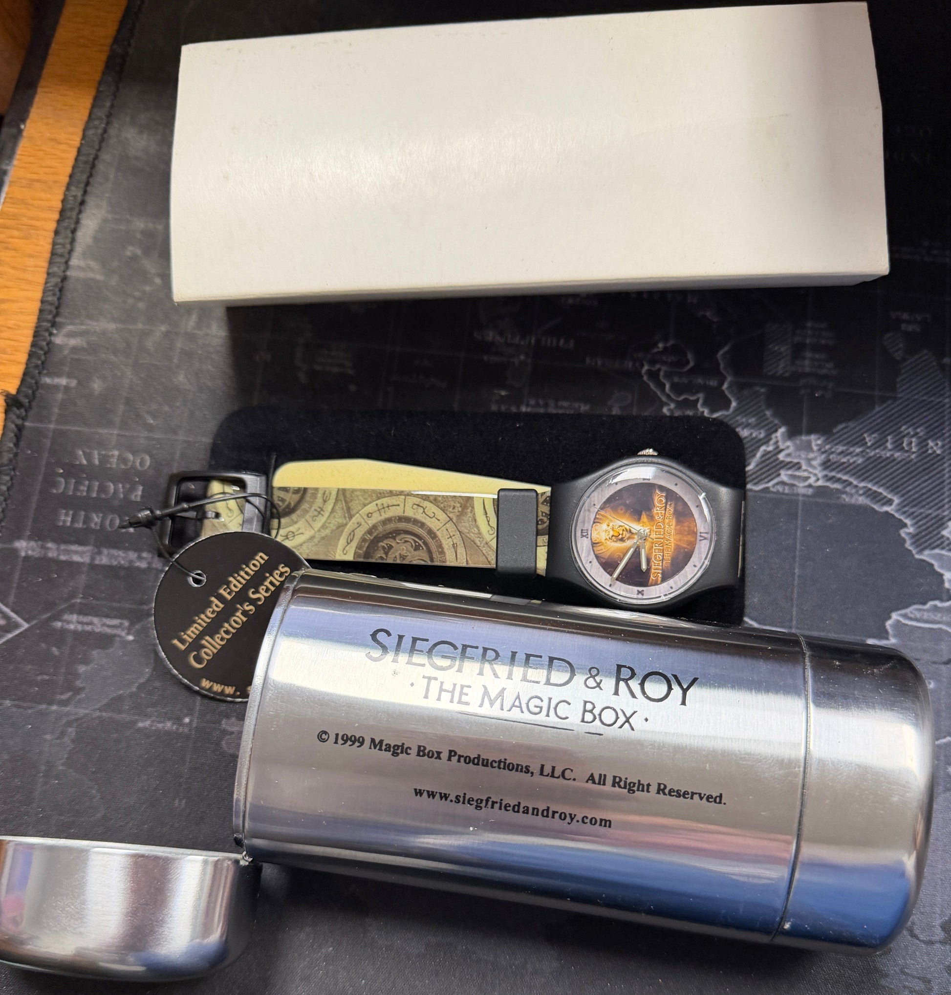 Silver cylindrical container with 'Siegfried & Roy' branding on a textured surface.