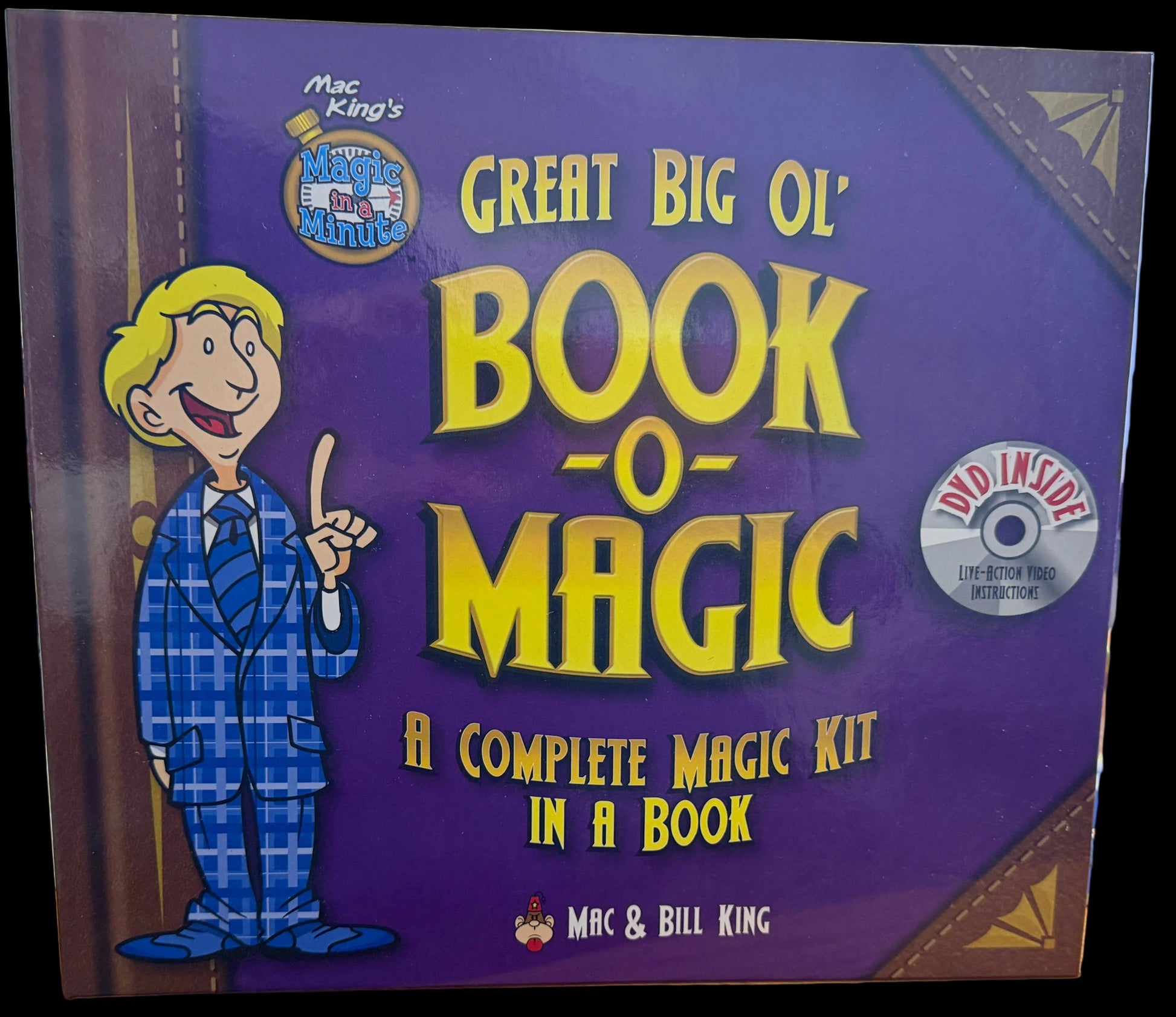 Book titled 'Great Big Ol' Book-o-Magic' on a desk with computer monitors in the background