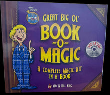 Book titled 'Great Big Ol' Book-o-Magic' on a desk with computer monitors in the background