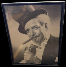 Framed black and white photo of a person with a map and computer screens in the background