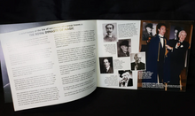 Open book with text and black and white photos on a dark background