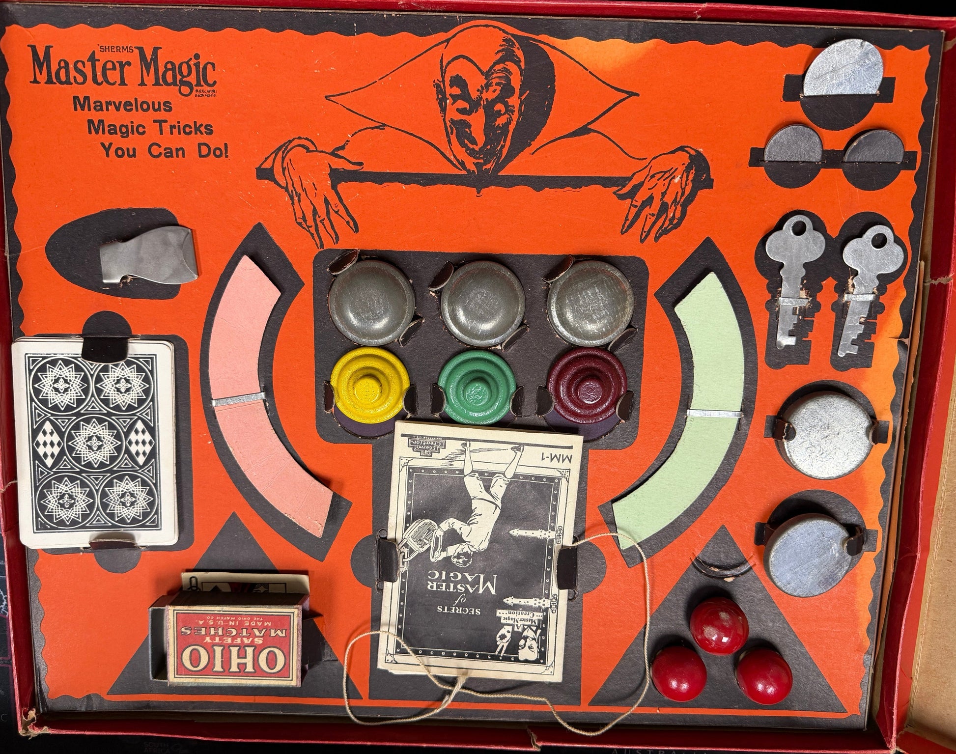 Vintage magic trick set with various components on an orange box labeled 'Ohio Master of Magic'.