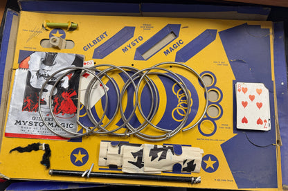 Vintage Gilbert Mysto Magic set with rings, cards, and other props on a yellow box.
