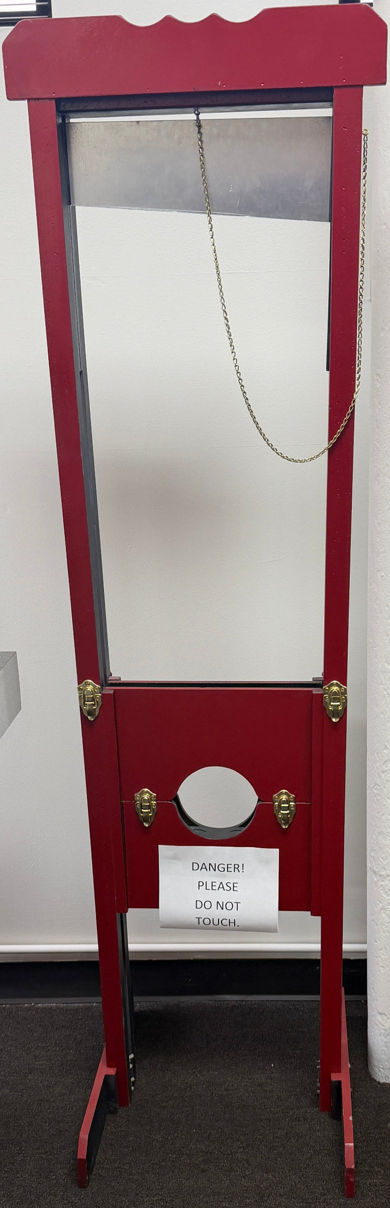 Red crossbow on a stand with books and a picture frame in the background