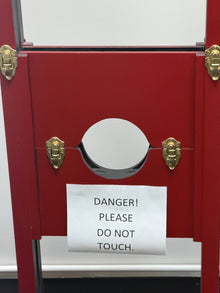 Red display case with gold accents and a 'Please Do Not Touch' sign.