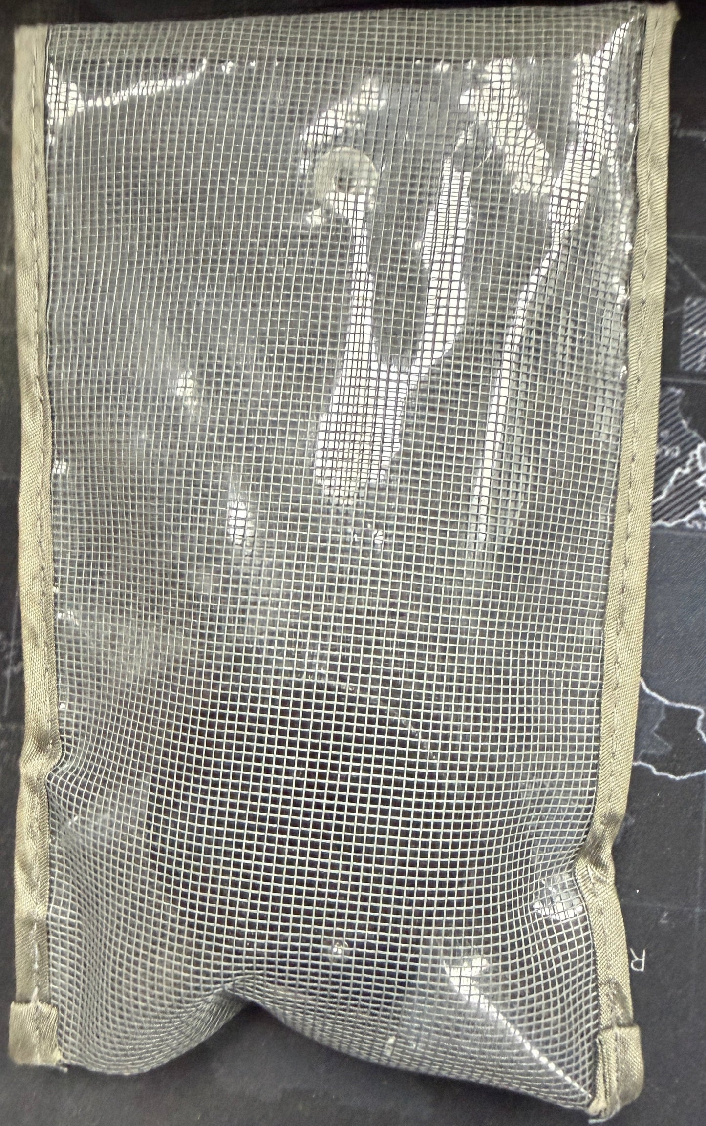 Mesh pouch on a dark surface with a map background