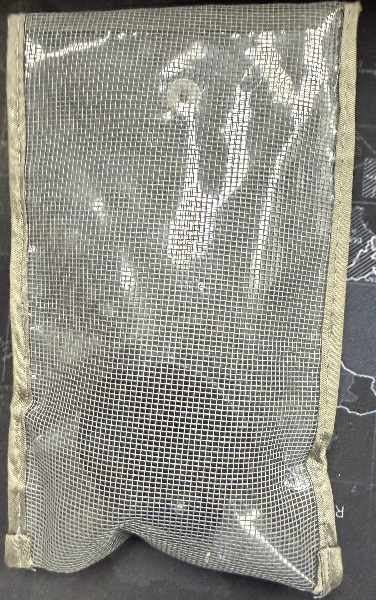 Mesh pouch on a dark surface with a map background