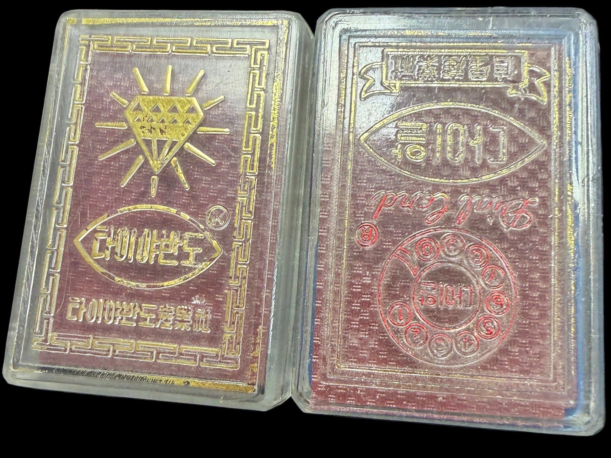 Two red and gold playing card decks on a textured surface