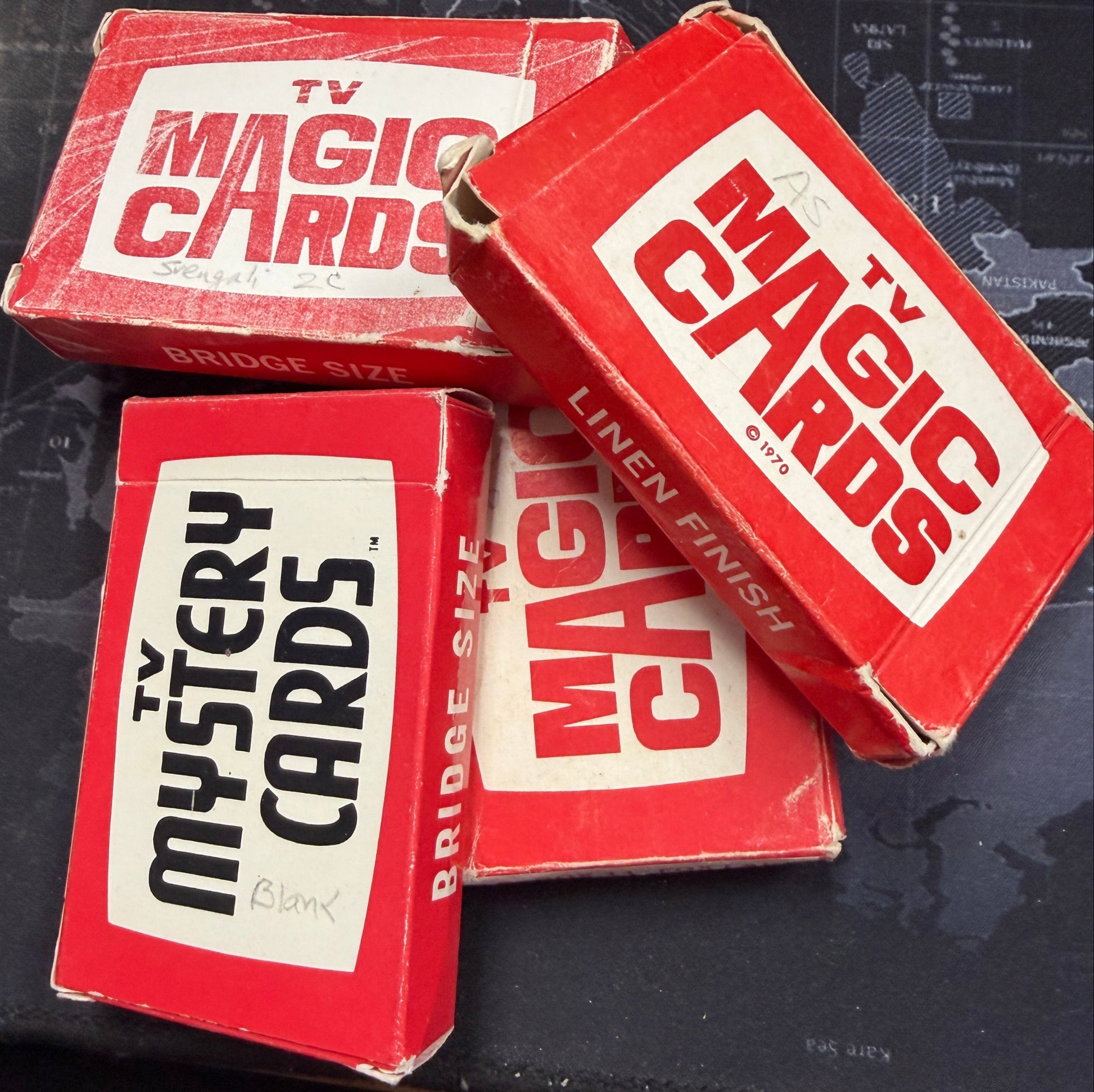 Four red boxes of TV Magic Cards on a dark surface