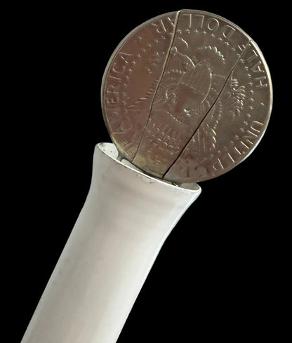 White handle with a coin inserted into it against a black background