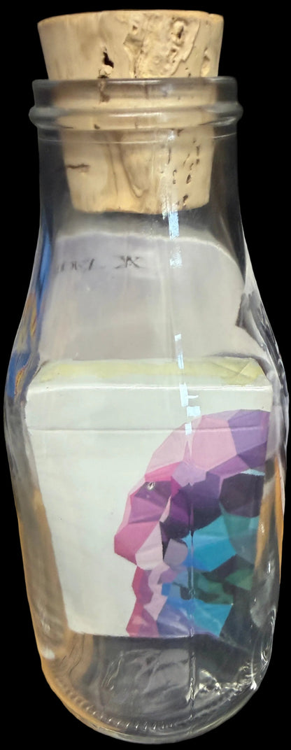 Bottle with cork lid containing a colorful skull design on a white background