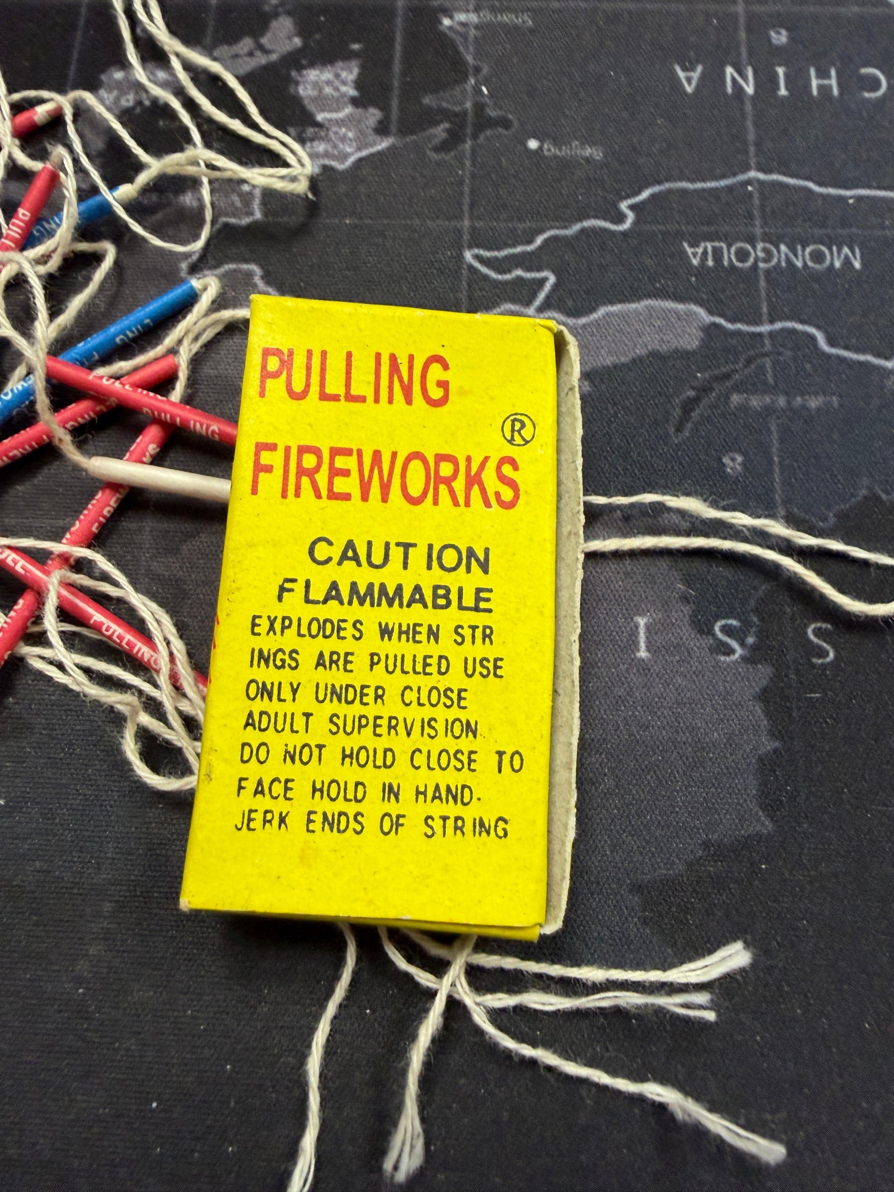 Fireworks pull string with warning label on a map background