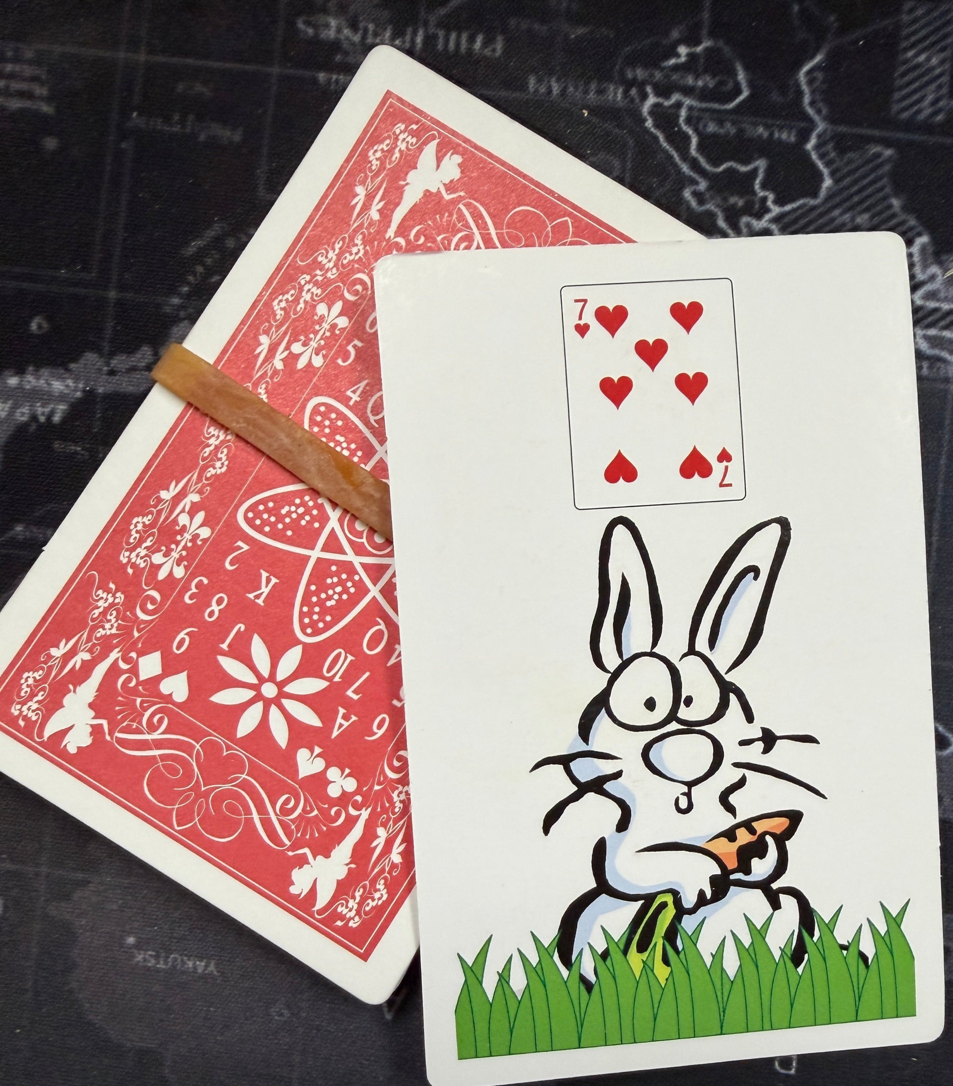 Two playing cards with a cartoon rabbit design on a dark textured surface