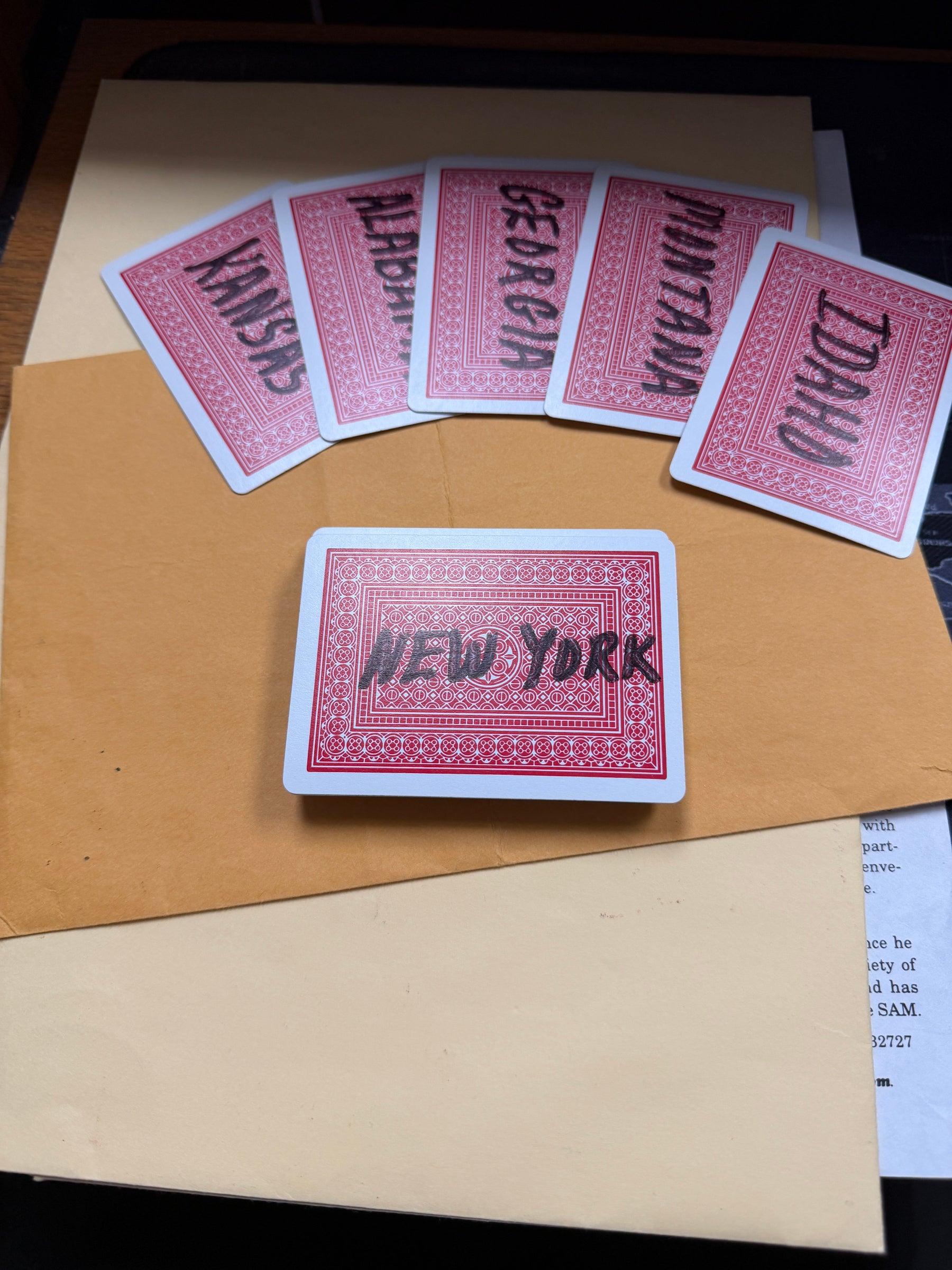 Set of red playing cards with state names on a brown surface