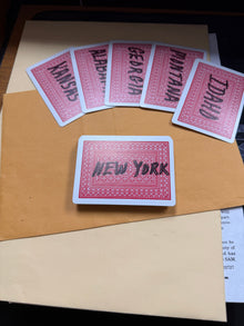 Set of red playing cards with state names on a brown surface