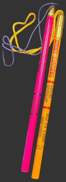 Two highlighters, one pink and one orange, on a black background.