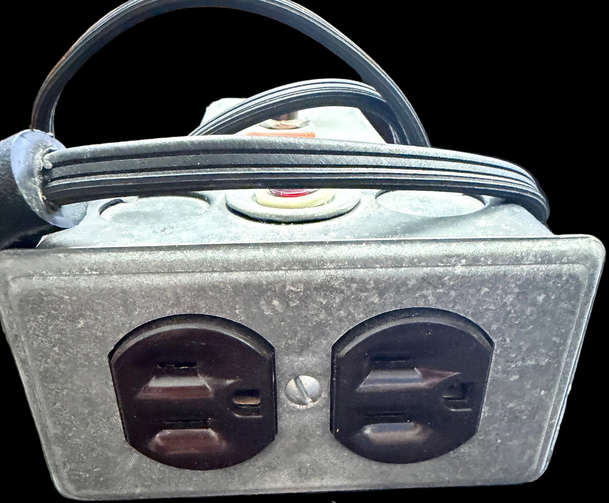 Metallic electrical outlet with two sockets on a textured surface.