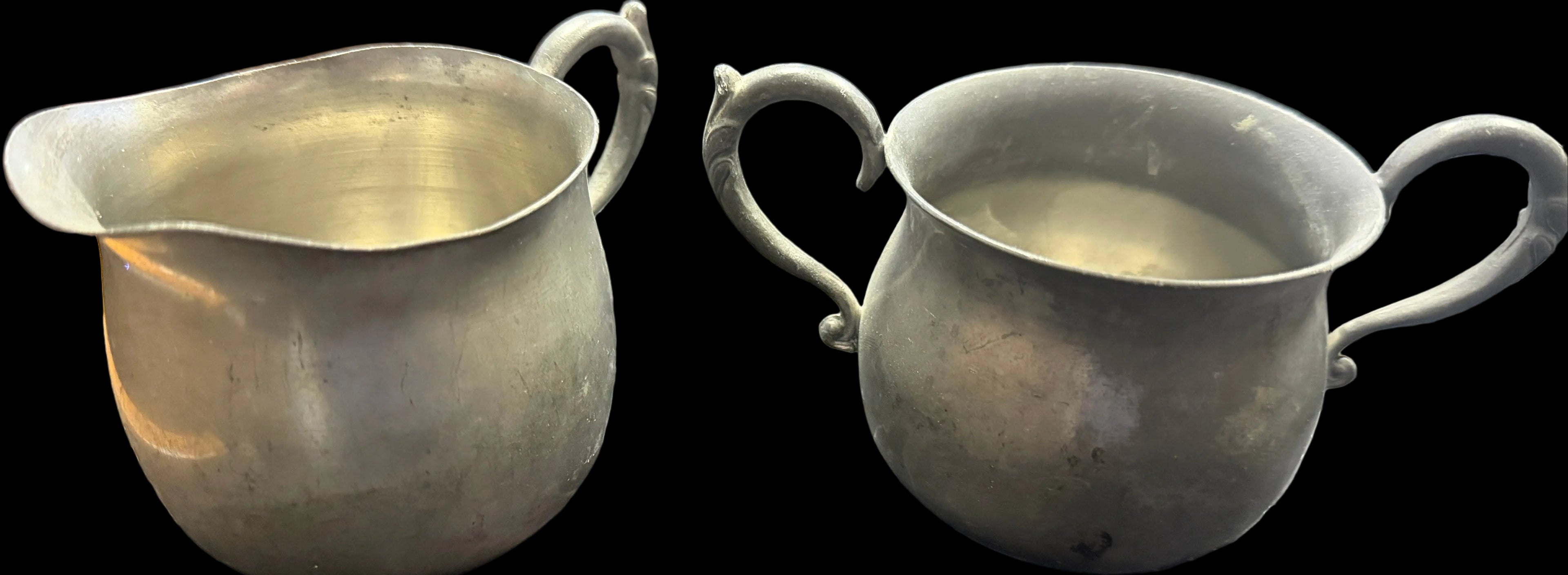 Two silver pitchers on a dark surface with a world map.