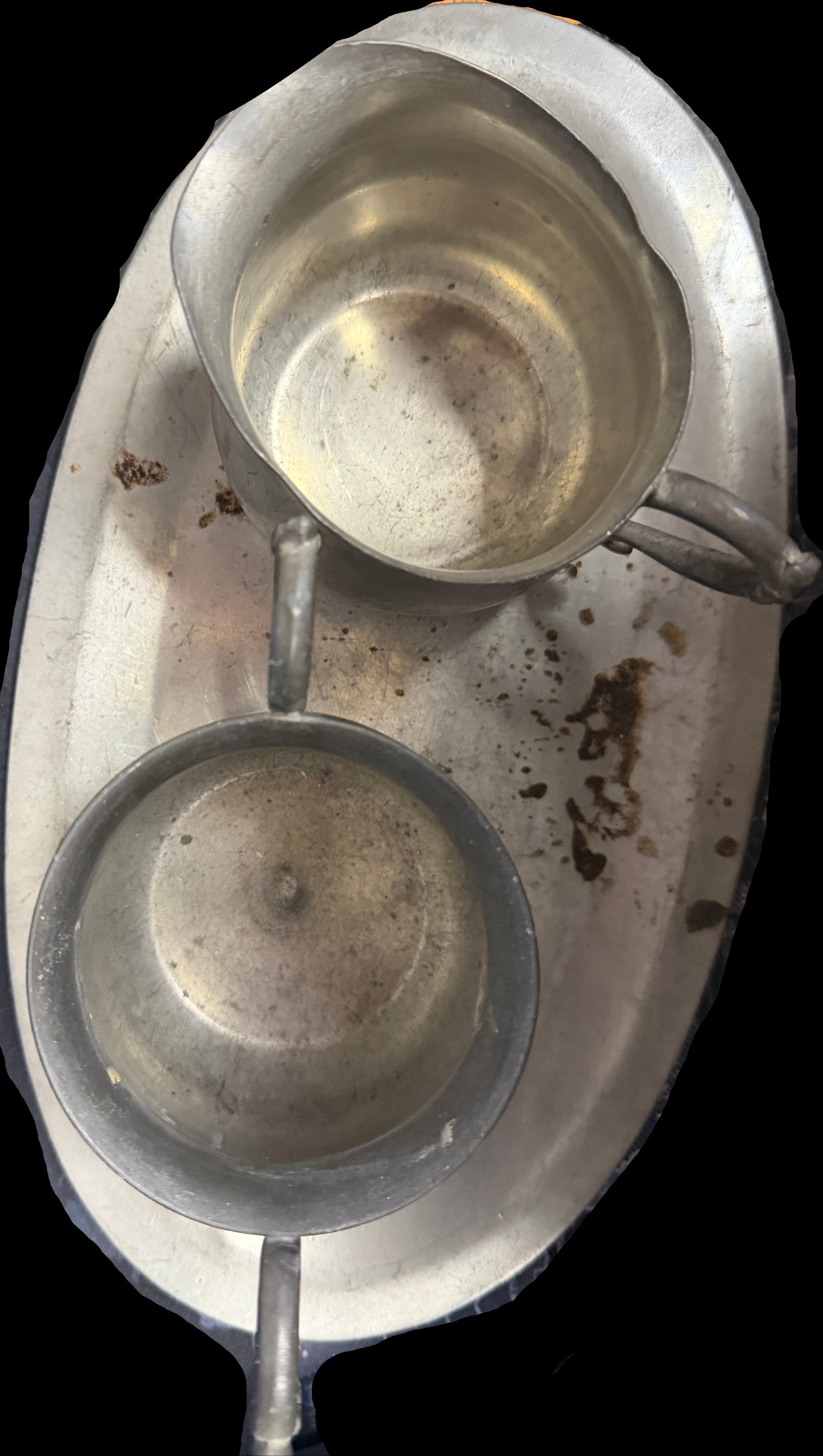 Two metal bowls on a tray with a worn surface, possibly on a desk.