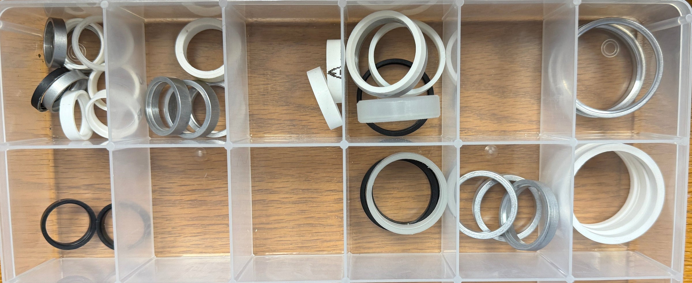 Clear plastic organizer with various metal washers on a wooden surface