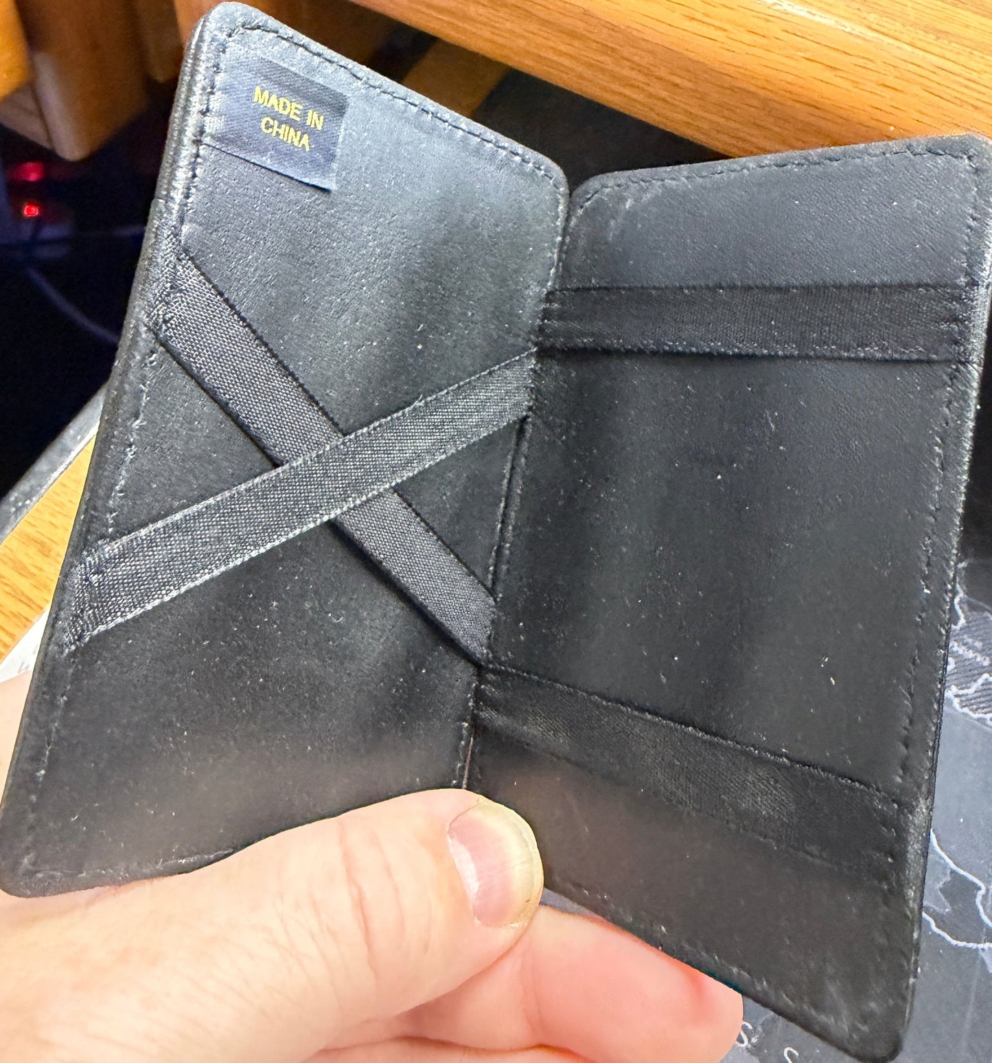 Black leather wallet held by a hand with a blurred background