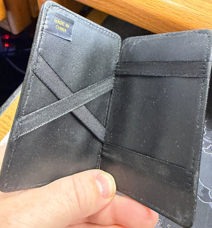 Black leather wallet held by a hand with a blurred background