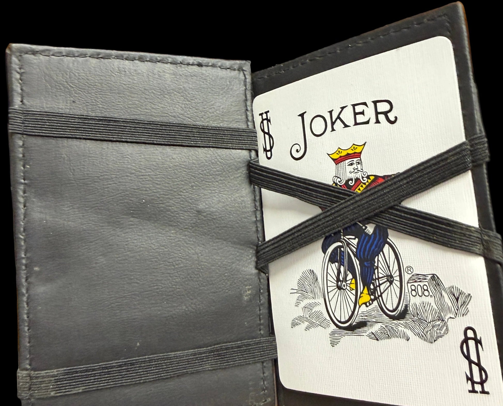 Black leather wallet with playing cards pulled out, showing a joker card.