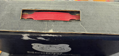 Close-up of a book with a red tool-like object inside, on a blurred background.